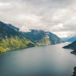 green mountains beside body of water under cloudy sky during daytime