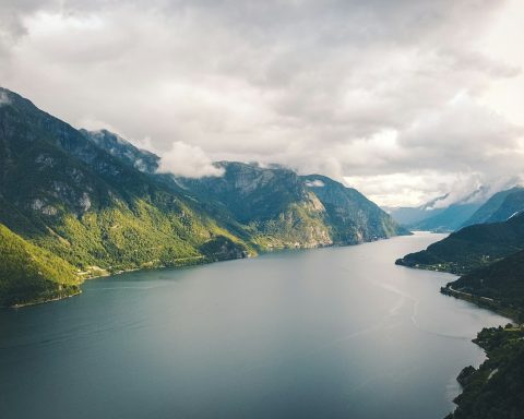 green mountains beside body of water under cloudy sky during daytime